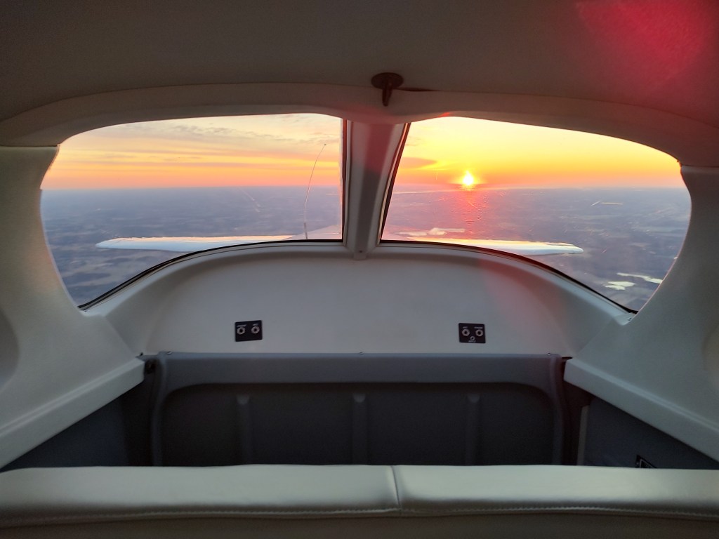 Looking through the rear windows of a small plane toward the sunrise.